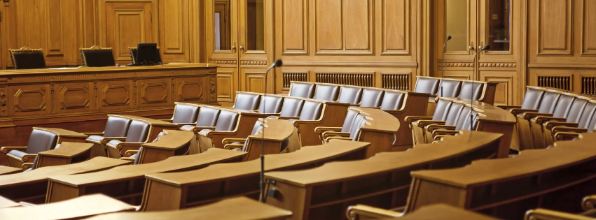 Holzgetäfelter Gerichtssaal mit leerer Geschworenenbank und Stühlen, mit geschnitzten Details und einer professionellen Atmosphäre eines Forderungseinzuges in Italien