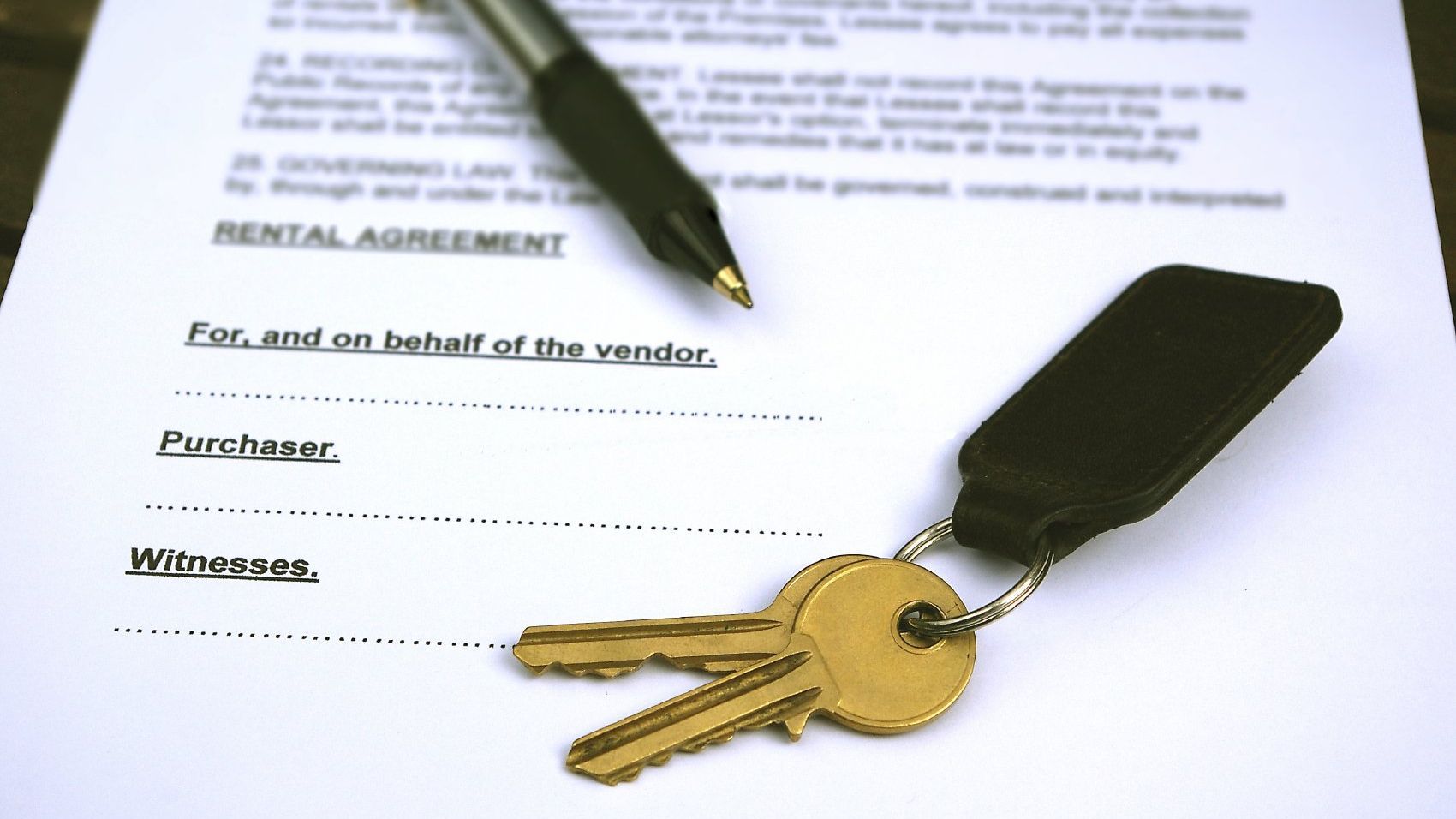 Key and a pen on a preliminary contract for a property under construction in Italy.