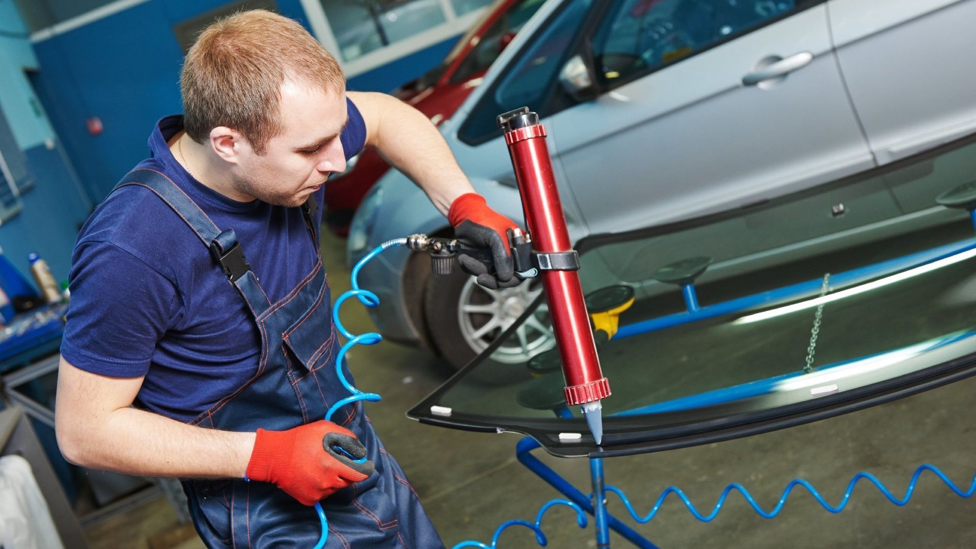 Mechaniker repariert oder ersetzt mit einem Werkzeug eine Windschutzscheibe an einem Fahrzeug nach einem Verkehrsunfall in Italien