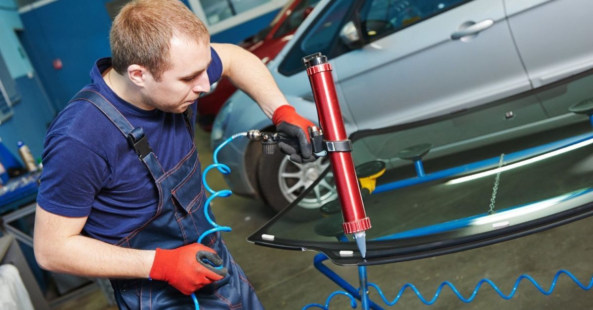 Mechaniker repariert oder ersetzt mit einem Werkzeug eine Windschutzscheibe an einem Fahrzeug nach einem Verkehrsunfall in Italien