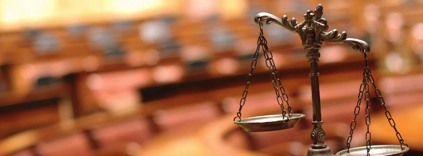 Nahaufnahme einer scharfen Gerechtigkeitswaage mit unscharfem Gerichtssaal-Hintergrund zum Thema Forderungseinzug  in Italien