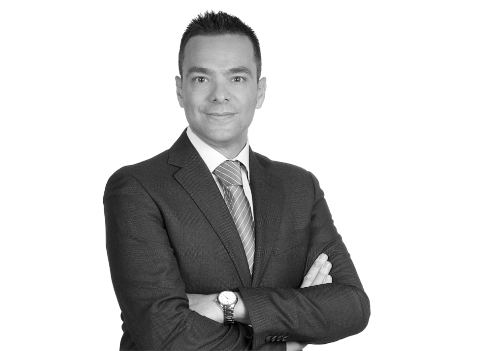 Gianluca Perencin Foto profilo di un avvocato italiano esperto a Monaco, specializzato in diritto italo-tedesco, in abito formale davanti allo sfondo del suo studio legale