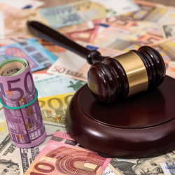 Ein Hammer auf einem Holzblock umgeben von verschiedenen internationalen Banknoten für einen Immobilienkauf