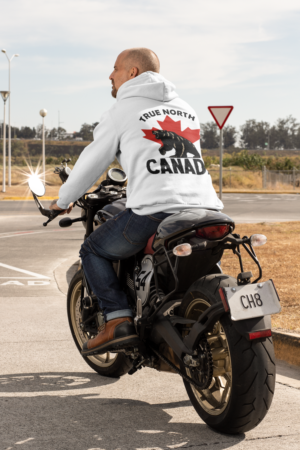 Man riding a motorcycle wearing a white ‘True North Canada’ bear hoodie.
