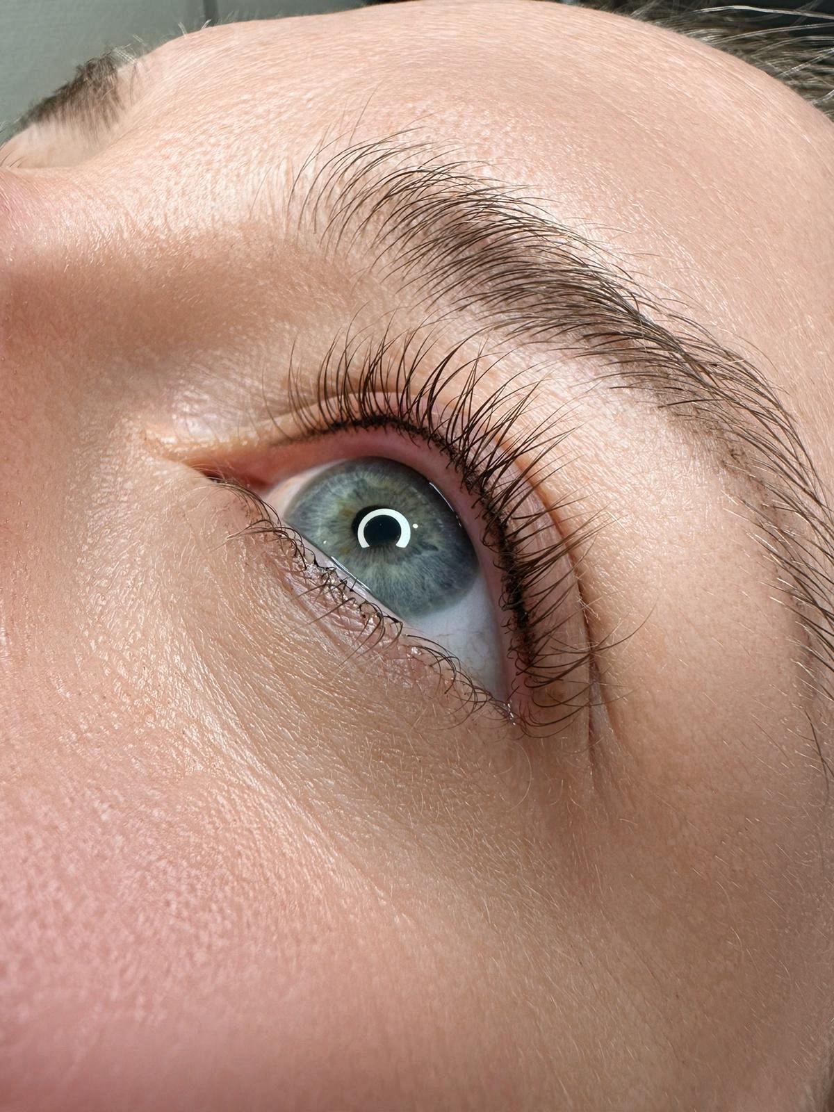 Nahaufnahme eines blauen Auges mit betontem Wimpernkranz nach einer Wimpernkranzverdichtung.