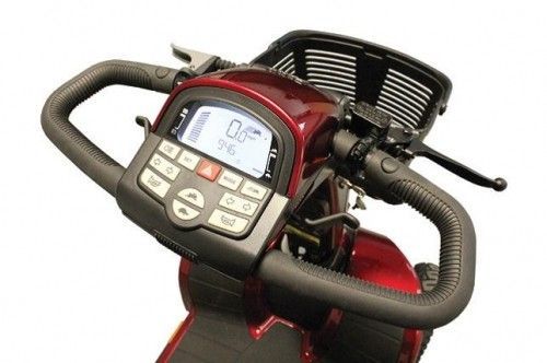 Gros plan sur le tableau de bord numérique d'un scooter électrique Pride Victory XL130 rouge, montrant l'écran d'affichage, les boutons de commande pour la vitesse, les lumières, l'avertisseur sonore et un panier avant.