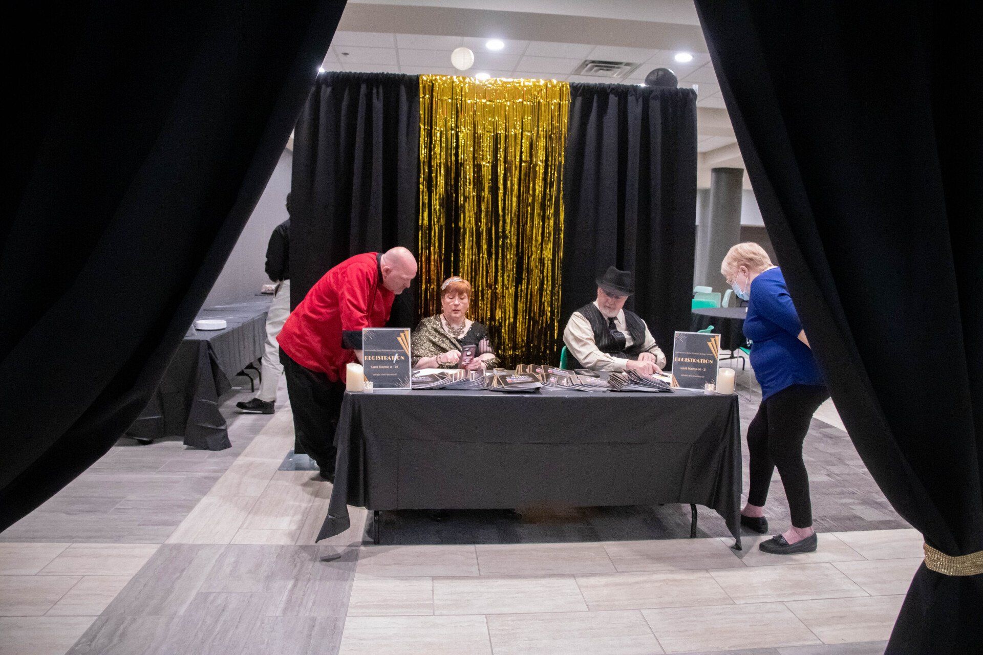 People at a registration table with black and gold decor.
