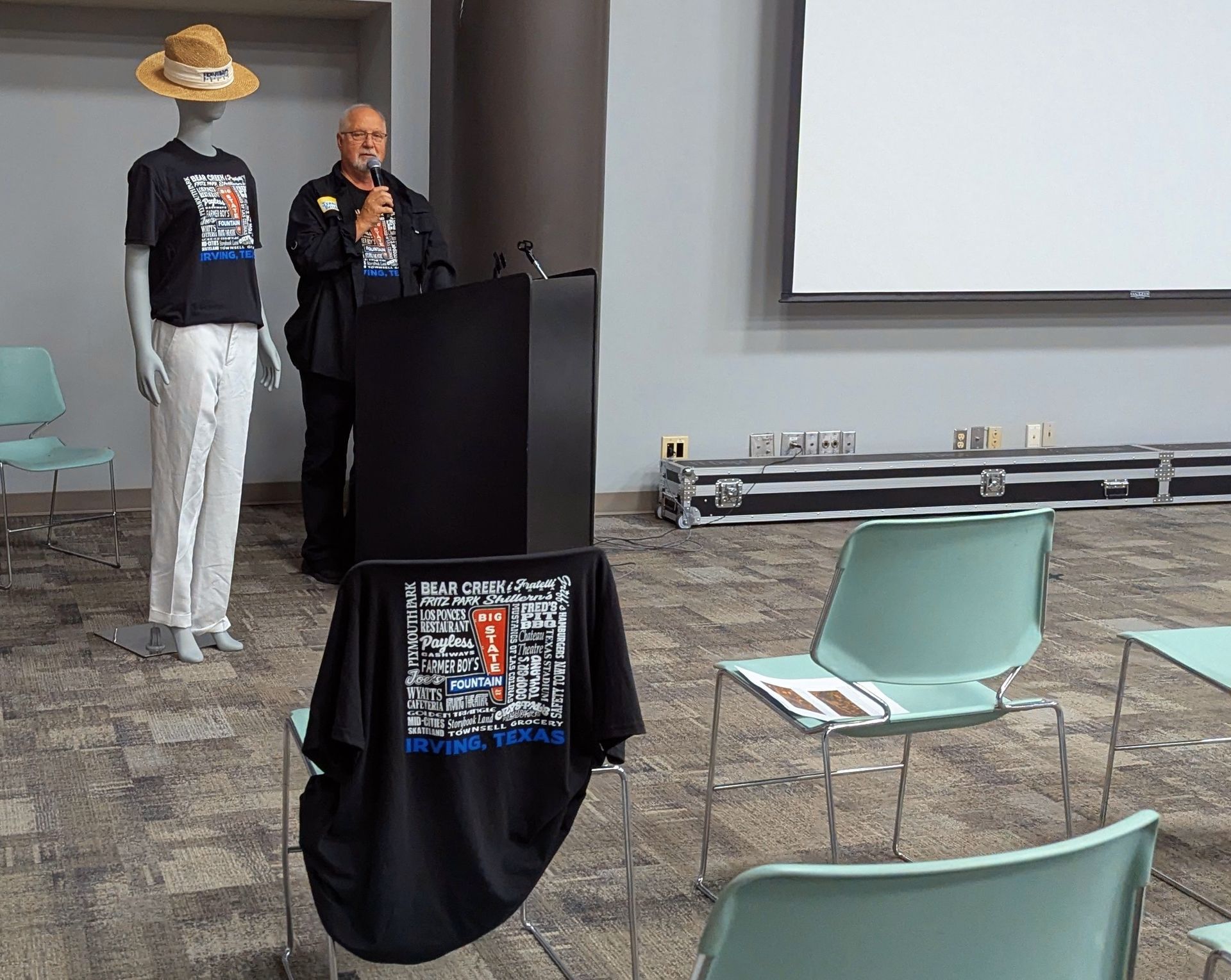 Man speaking at podium next to mannequin in