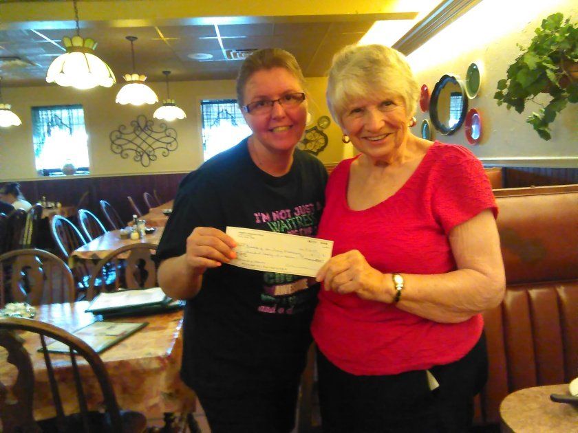 Two women holding a check in a restaurant.