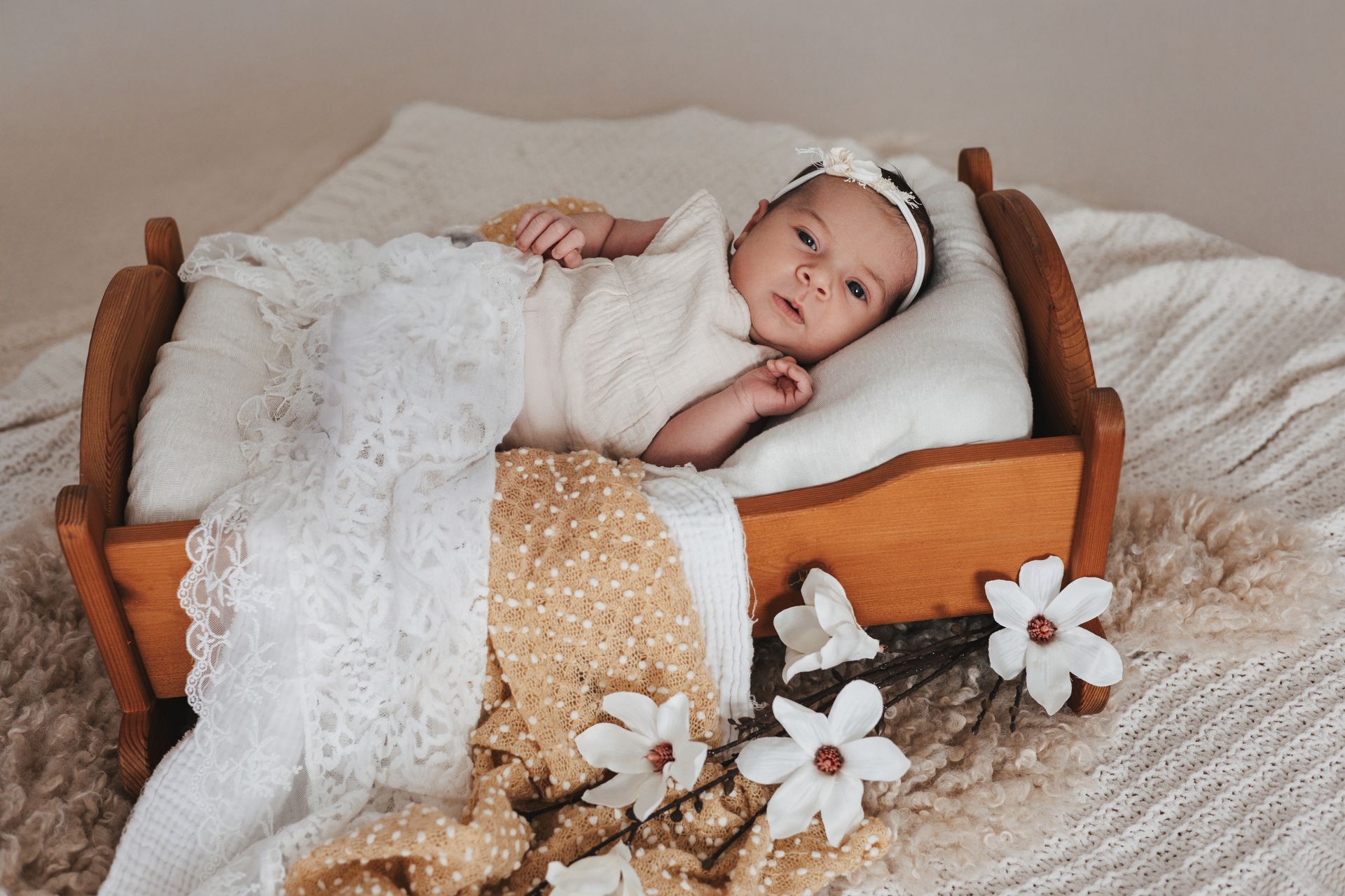 Neugeborenes Baby im Holzbett mit weißen Blüten