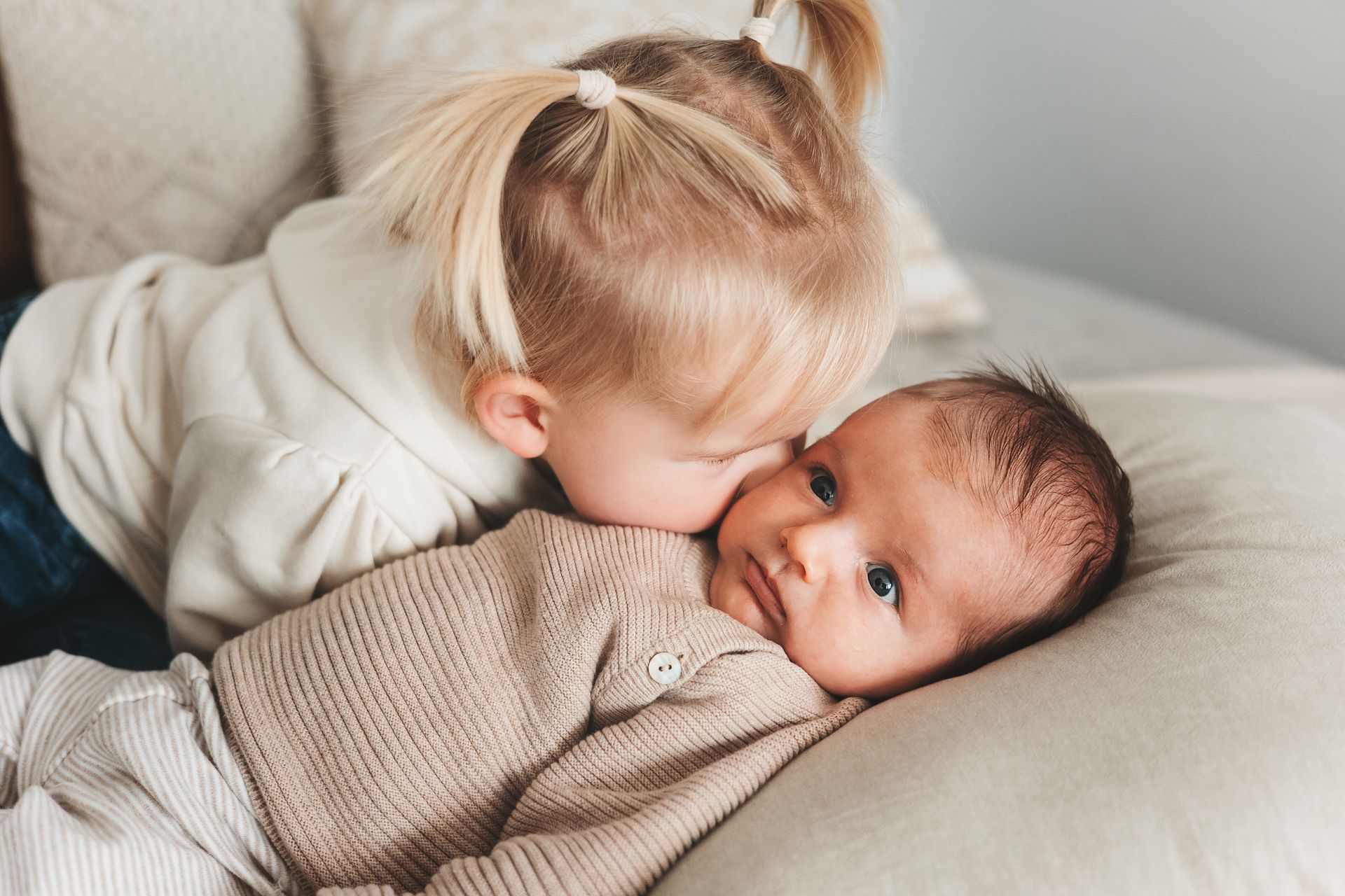 Schwester küsst neugeborenes Baby