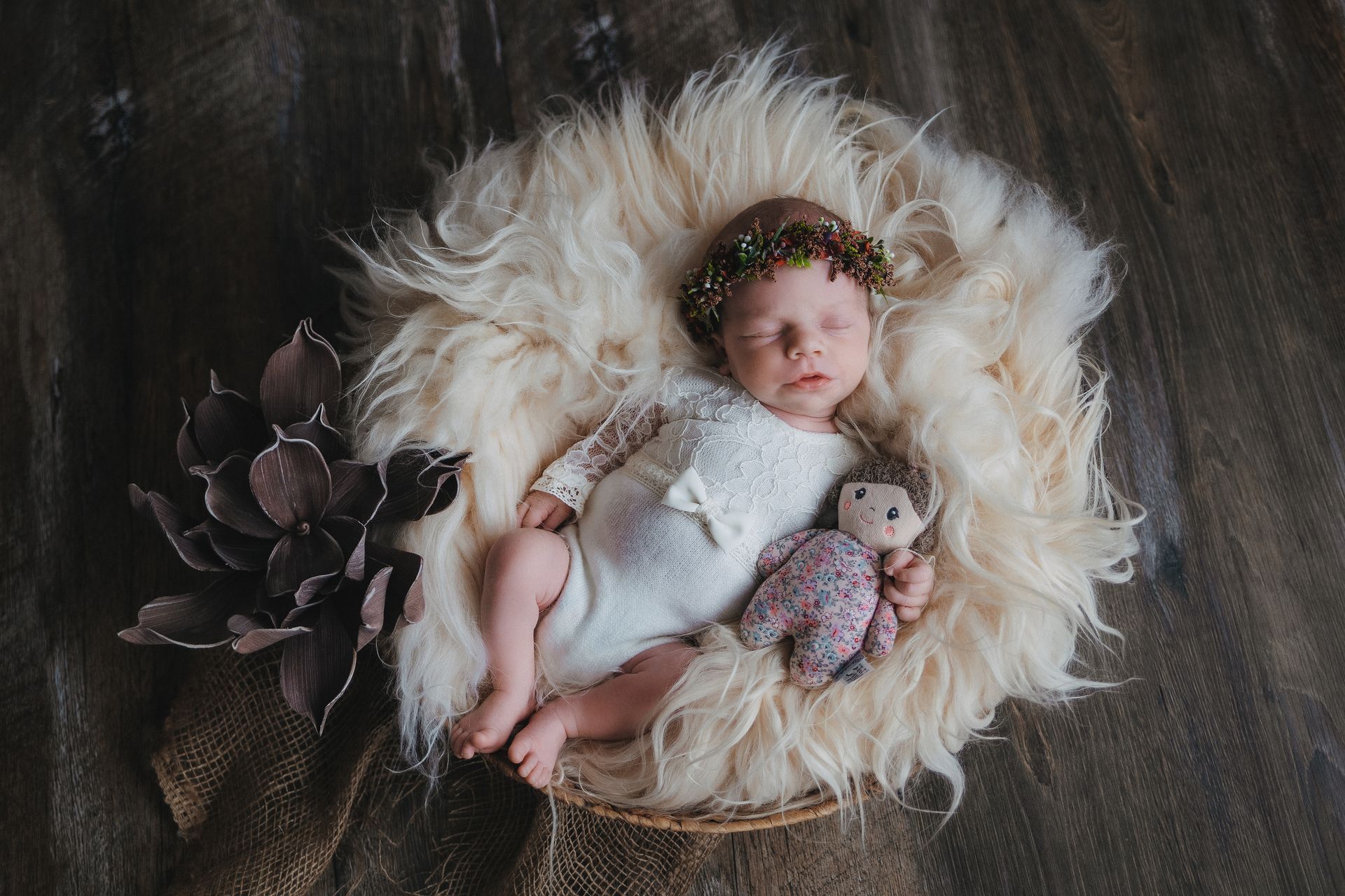 Neugeborenes Baby mit Blütenkranz im Korb