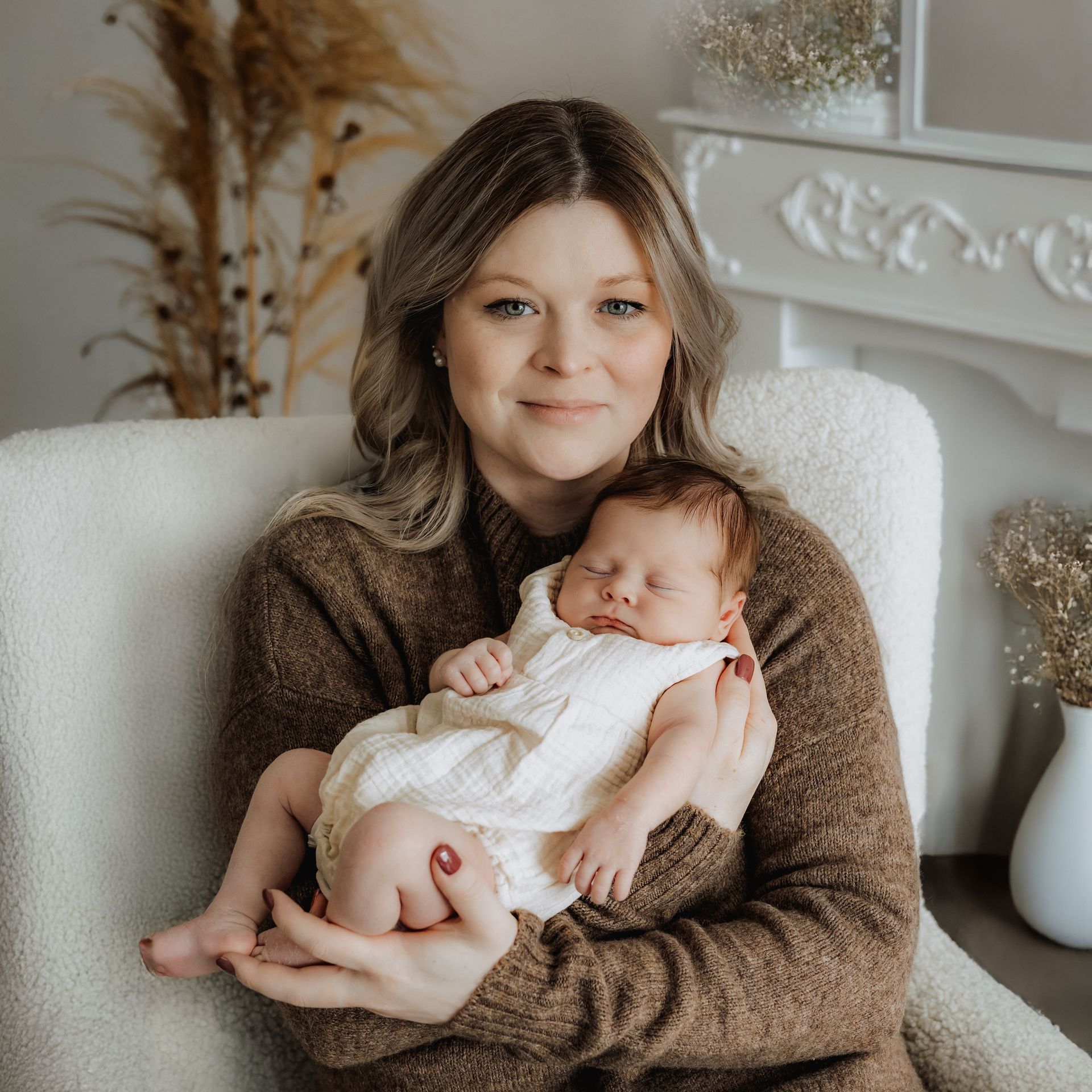 Neugeborenes Baby mit Mutter in einem weißen Sessel