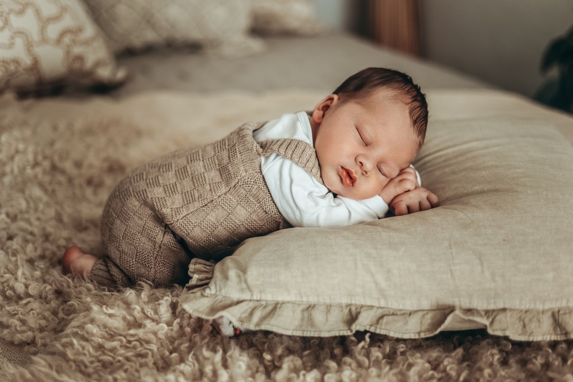Neugeborenes Baby mit Latzhose schläft