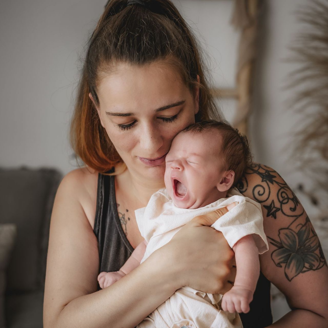 Neugeborenes Baby gähnt im Arm der Mutter