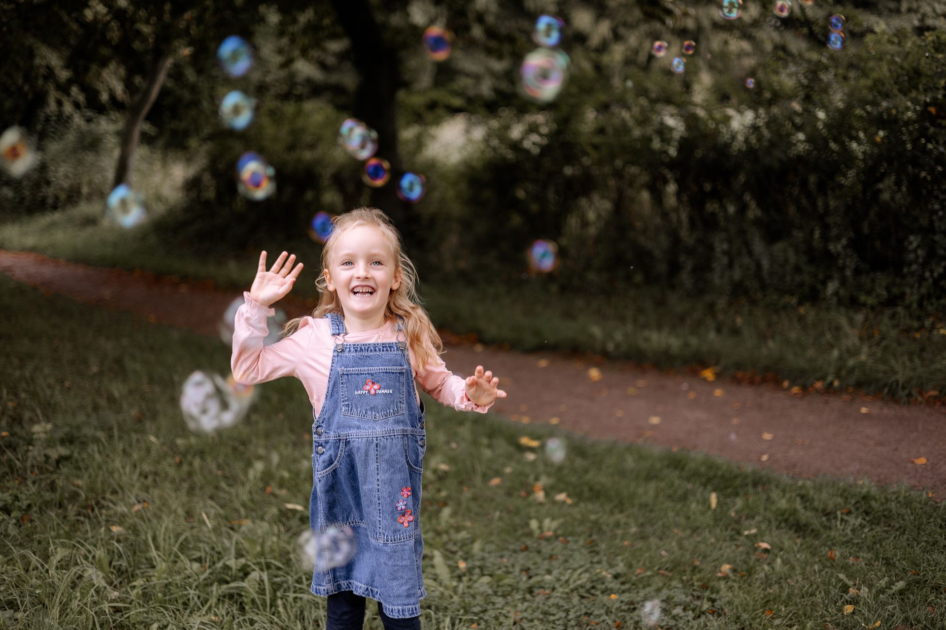 Kind tanzt beim Familienfotoshooting in Seifenblasen
