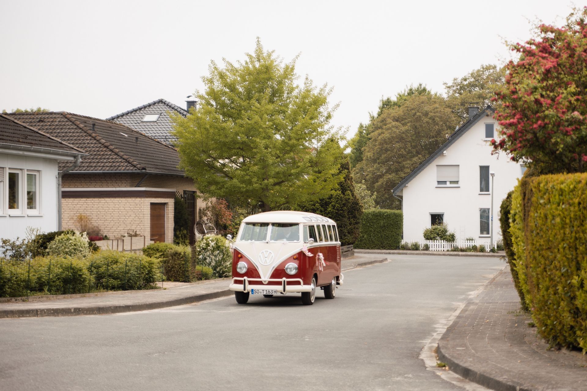 Brautvater überrascht Braut Maren mit einem roten VW Bulli Oldtimer vor ihrem Zuhause.