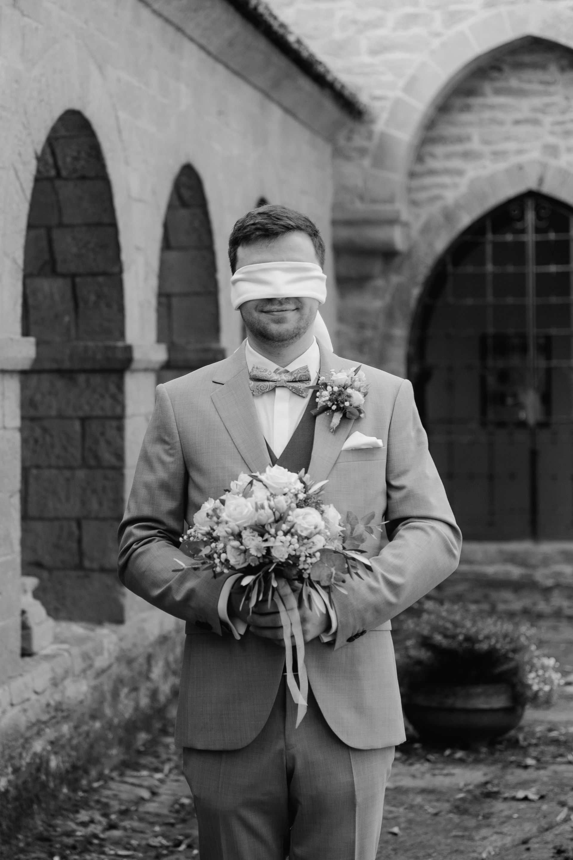 Der Bräutigam mit verbundenen Augen beim First Look, bereit, seine Braut zu sehen