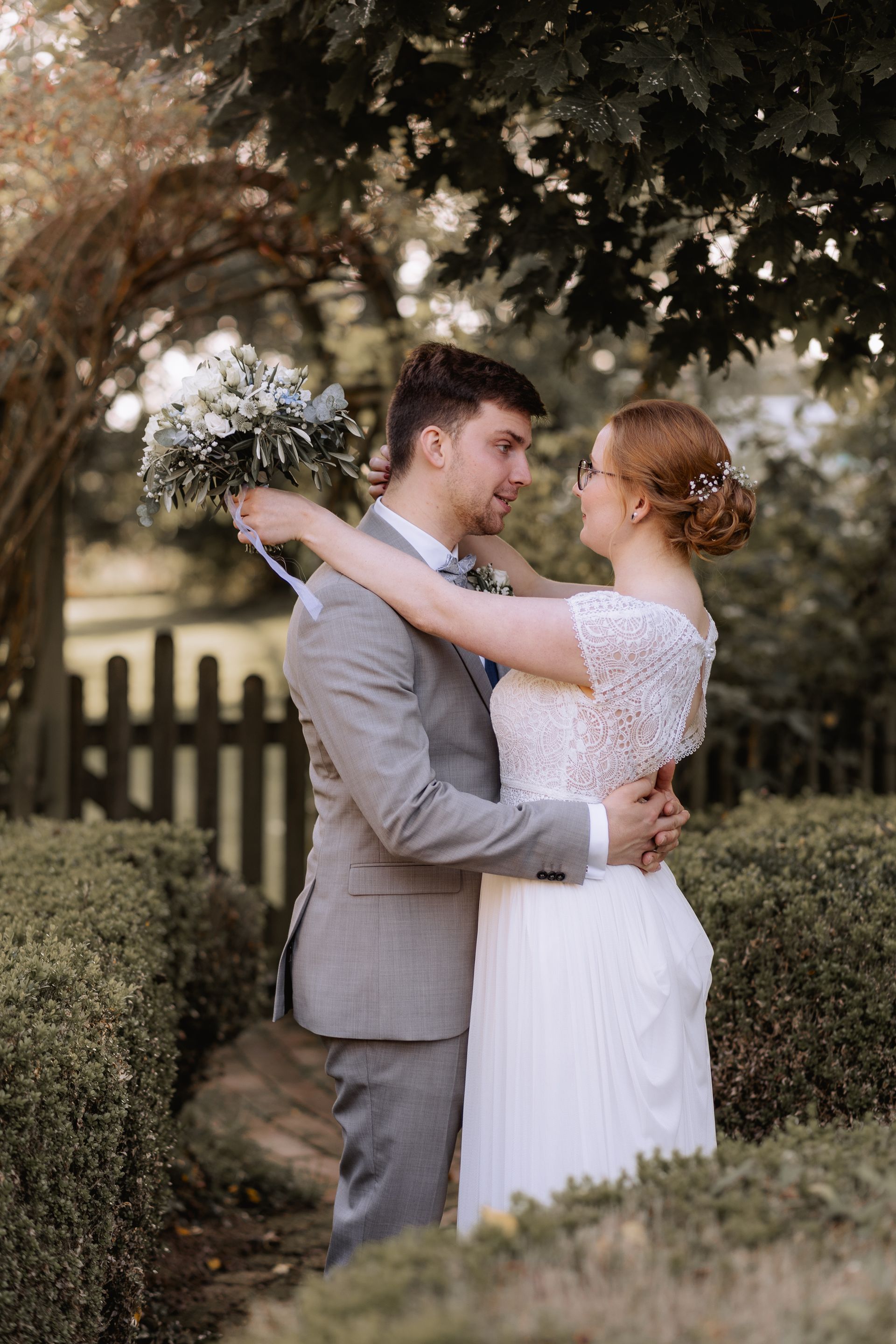 Das Brautpaar umarmt sich liebevoll beim Fotoshooting vor dem Thinghof, während sie schöne Erinnerungsfotos machen