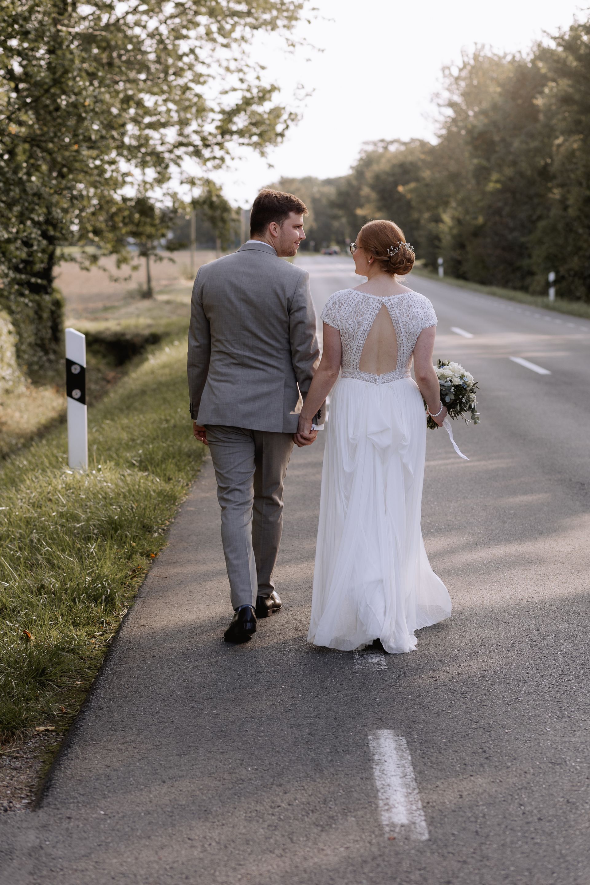 Brautpaar läuft Hand in Hand die Straße entlang