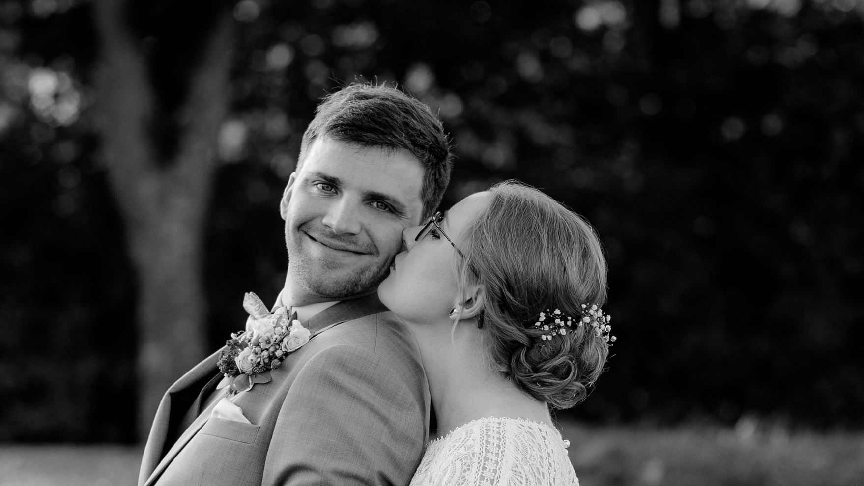 Braut küsst dem Bräutigam zärtlich auf die Wange