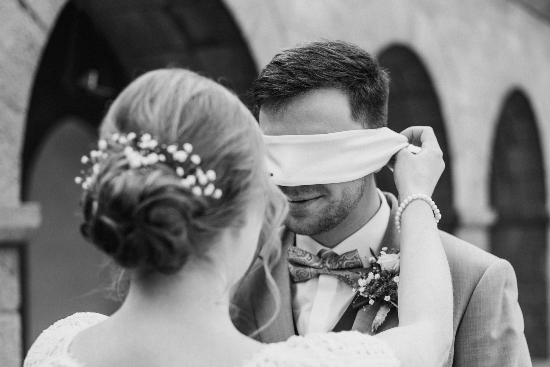 Die Braut nimmt ihrem zukünftigen Ehemann vorsichtig die Augenbinde ab