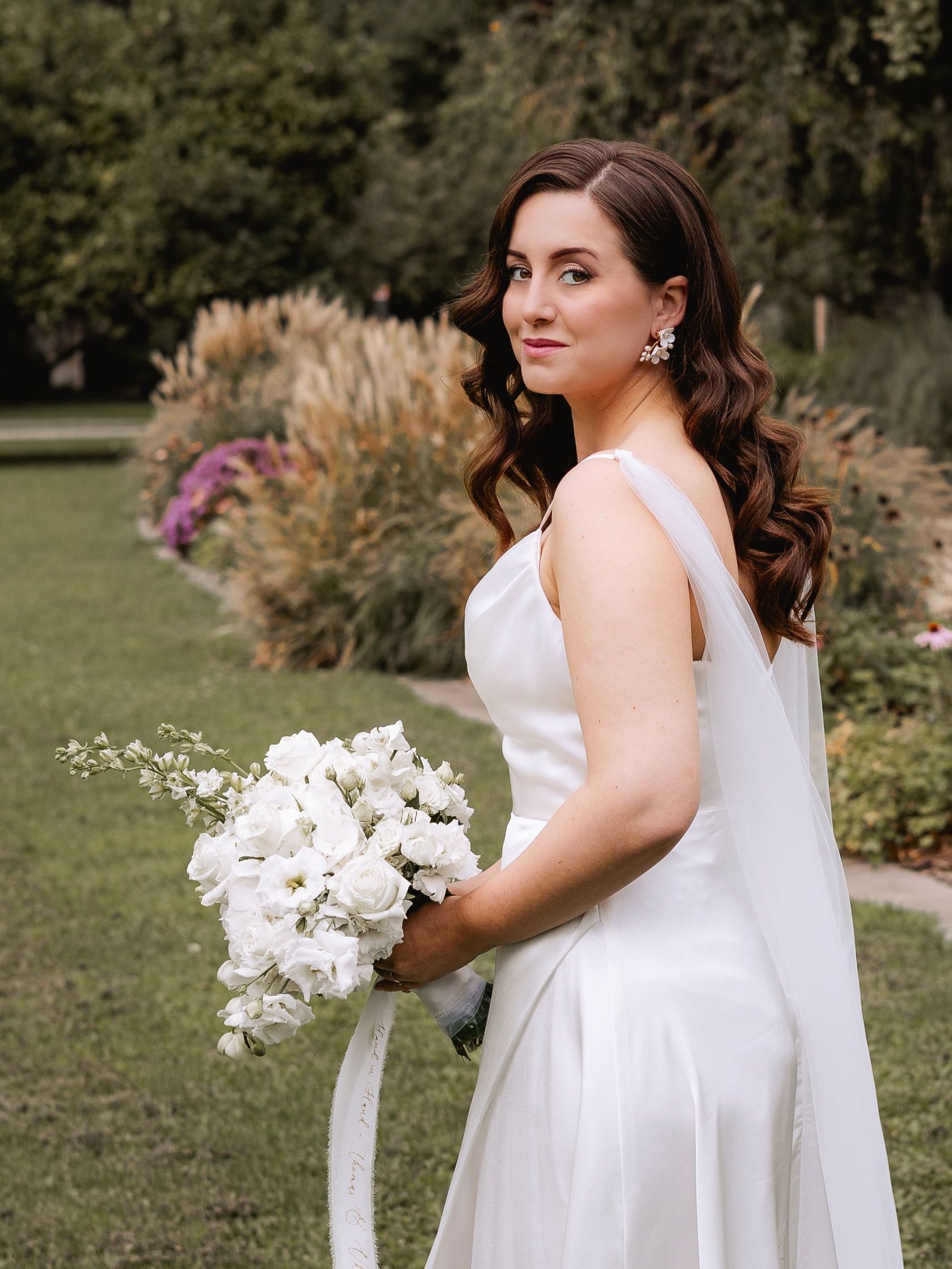 Braut im Rosengarten mit weißen Blumen