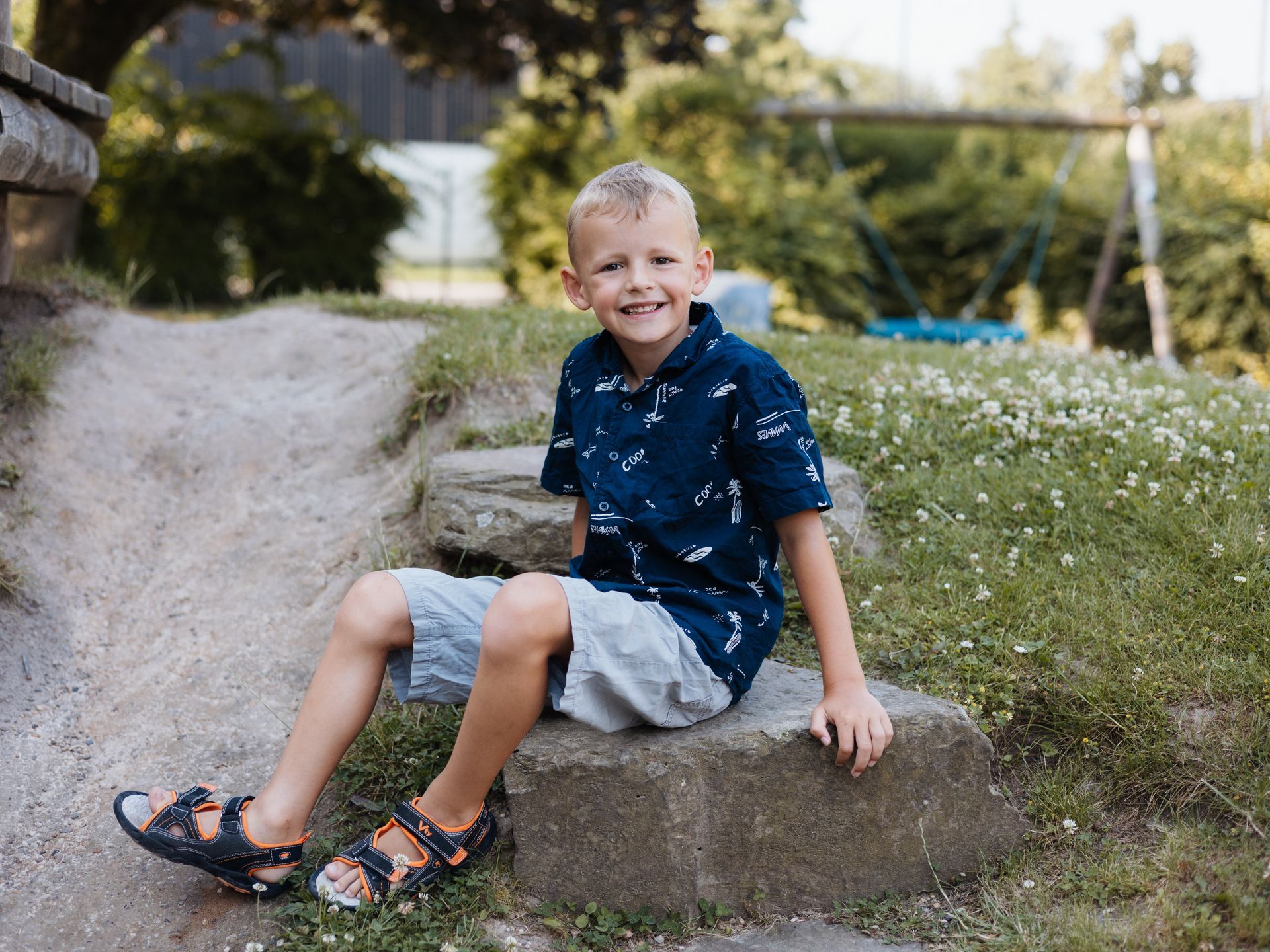 Kind sitzt auf großen Steinen vom Kindergarten Spielplatz