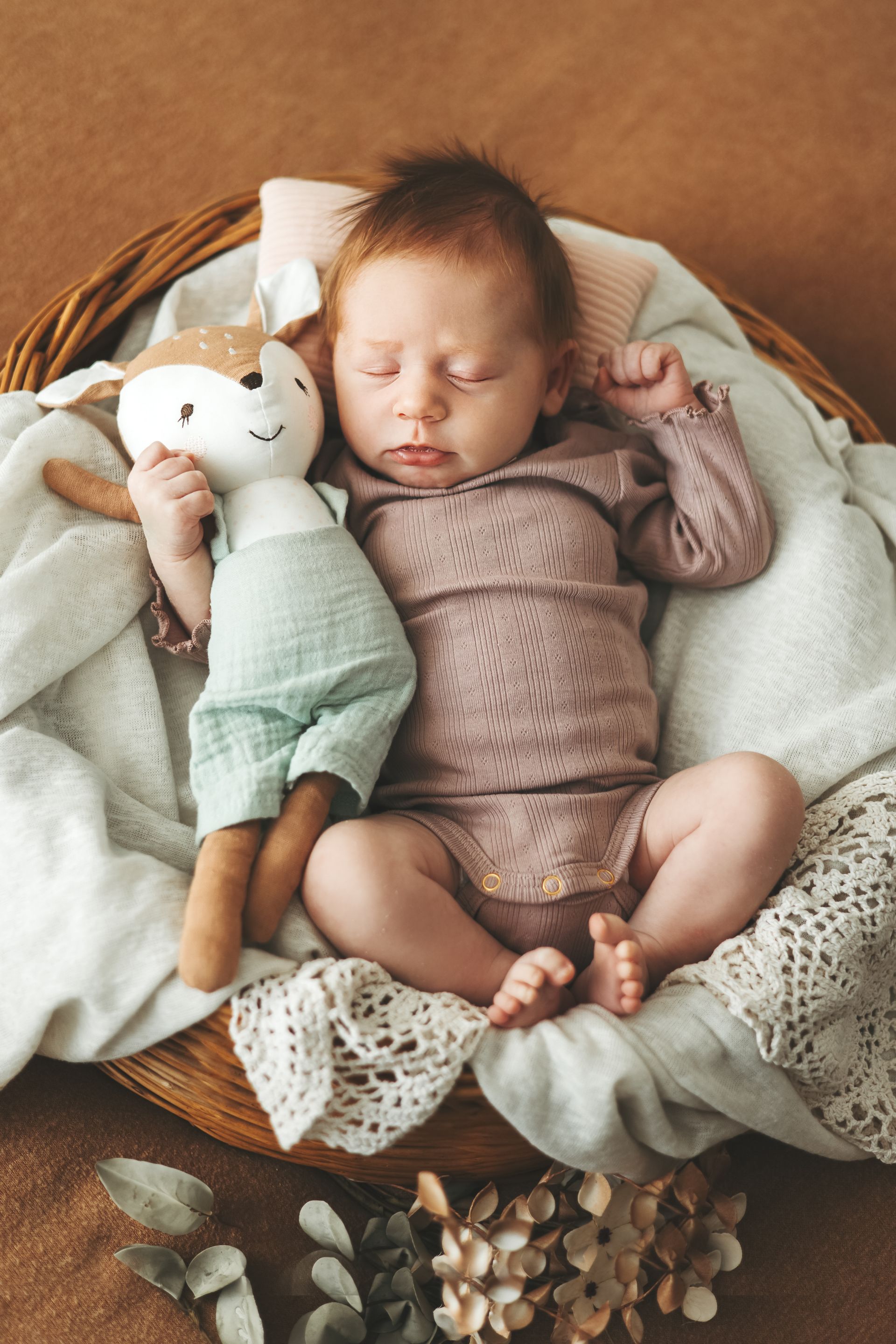 Neugeborenes Baby entspannt mit einem Reh Kuscheltier