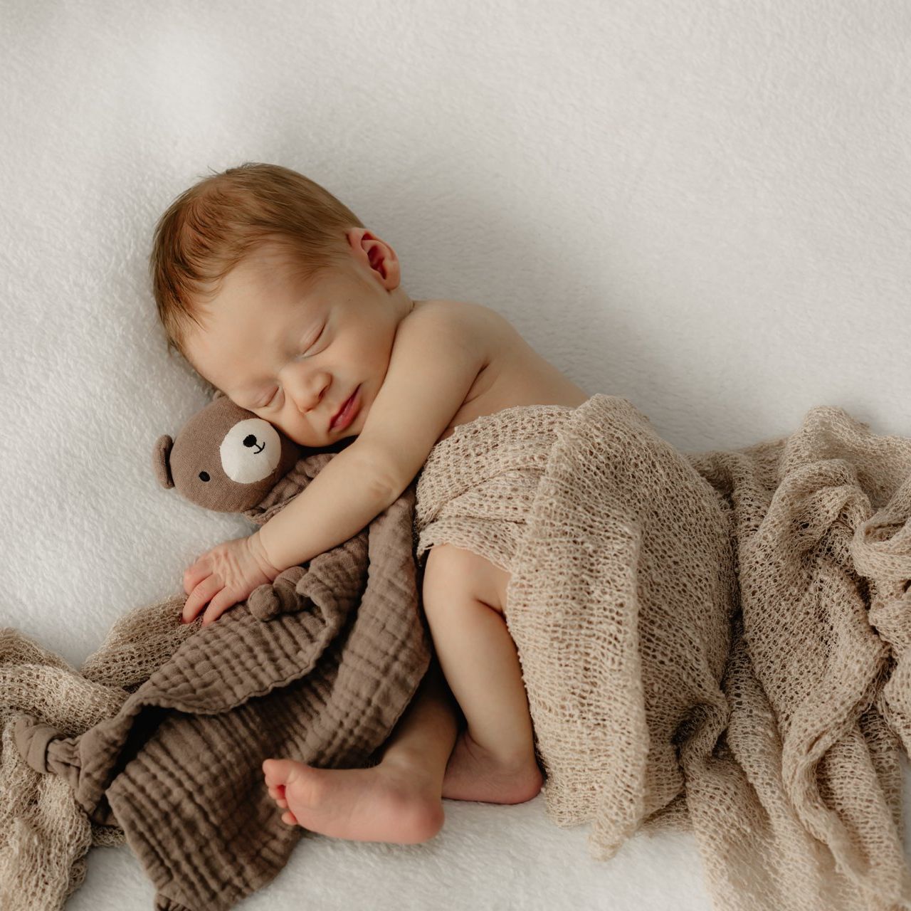 Neugeborenes Baby kuschelt mit einem Teddy