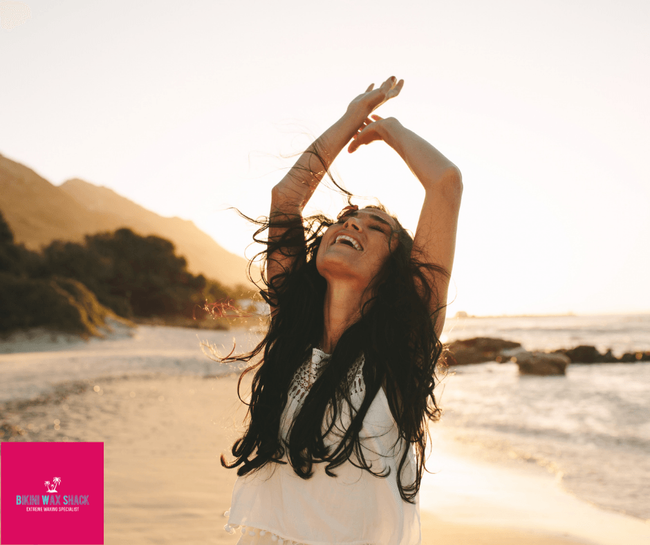 Girl on the beach with her arms up in the air smiling