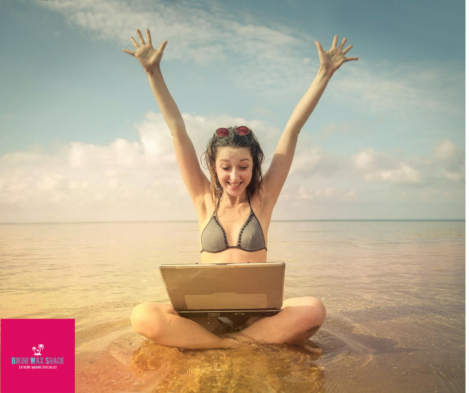 Excited lady sat crossed legged in the sea with a laptop