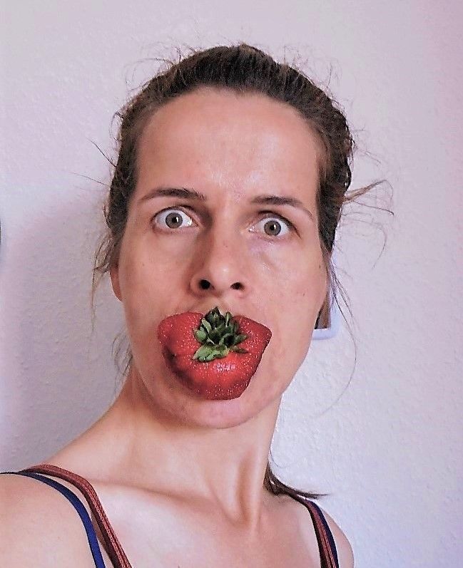 Antje Witzel selbst. Sie hab eine riesige Erdbeere vor ihren Mund geparkt und schaut mit aufgerissenen Augen in die Kamera, die mittellangen dunkelblonden Haare streng zum Zopf gebunden.