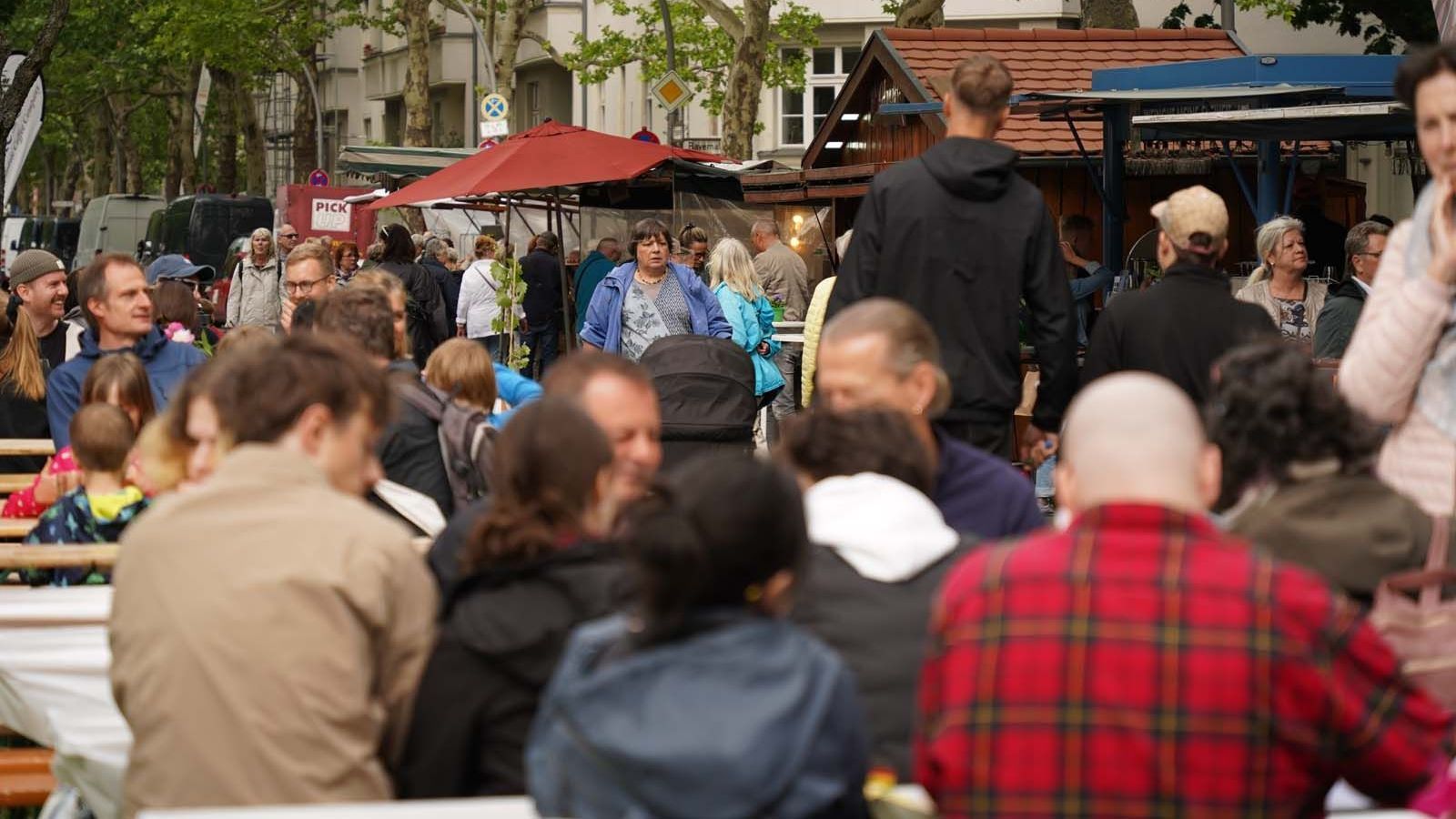 WeinPfingsten in Westend gut besucht! Alle Plätze beim Wein- und Winzerfest Westend besetzt – im Hintergrund die Wagen von manch einem Weingut.