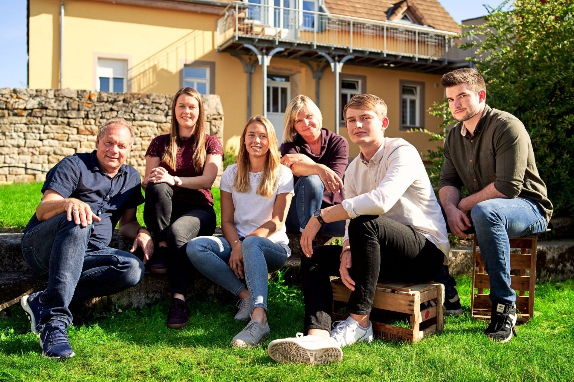 Die Winzerfamilie Schoenfeld vom Chumbderhof sitzt vor ihrem Weingut in Bornheim – seit 1683 mit Herz und Hand im Familienbetrieb vereint