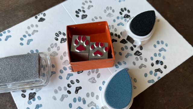 Gerhard Peterichs Werktisch mit Stempel und Stempelkissen. Das Motiv sind Hundepfoten.