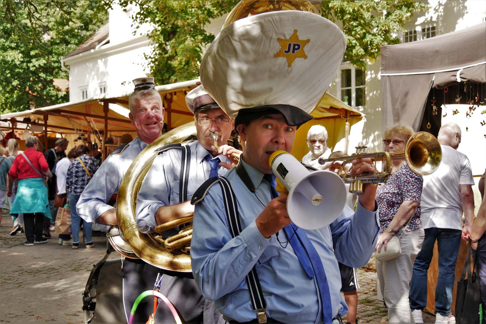 Die Jazzpolizei beim Wein- und Winzerfest Lichtenrade. Bei Sonnenschein zieht sie fröhlich an den Ständen von Kunst, Handwerk und Design vorbei.