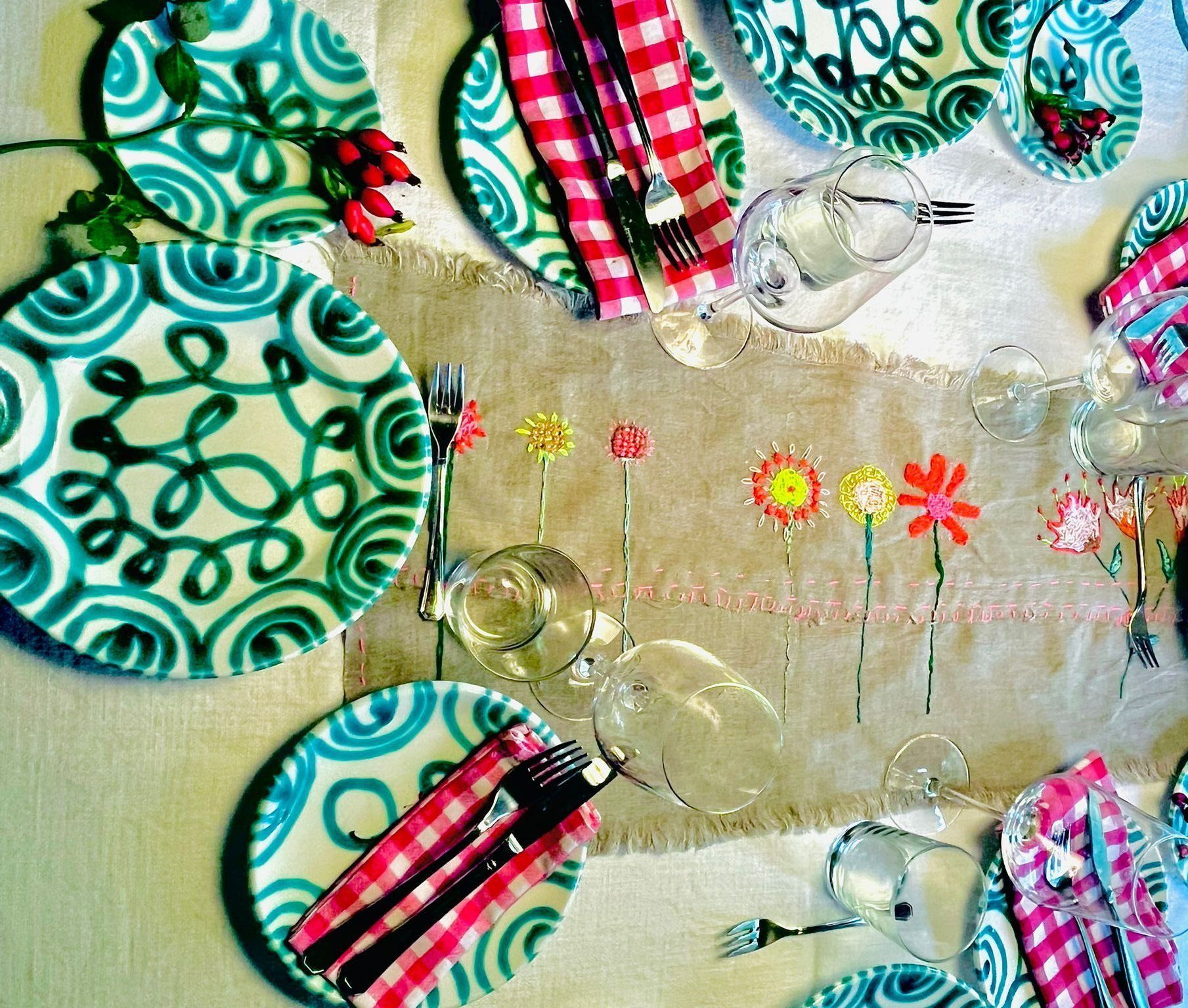 Joanna Wollerts Tischkultur Joanna Wollert deckt den Tisch einfach zauberhaft ein: mit grobem Leinentuch als Tischläufer in der Mitte, bestickt mit Herbstblumen, Bauernleinen rot-kariert als Stoffservietten und Teller mit grünem Ornament.