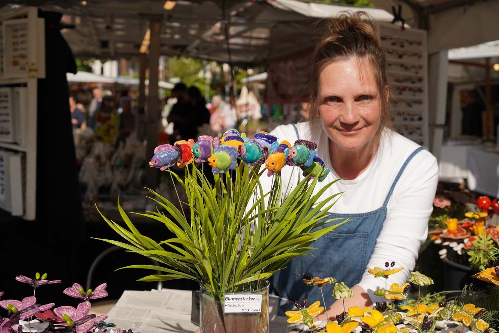 Sascha Dommengét zeigt bunte Keramik‑Fische und Schmetterlinge an ihrem Marktstand -KUNST am Sonntag