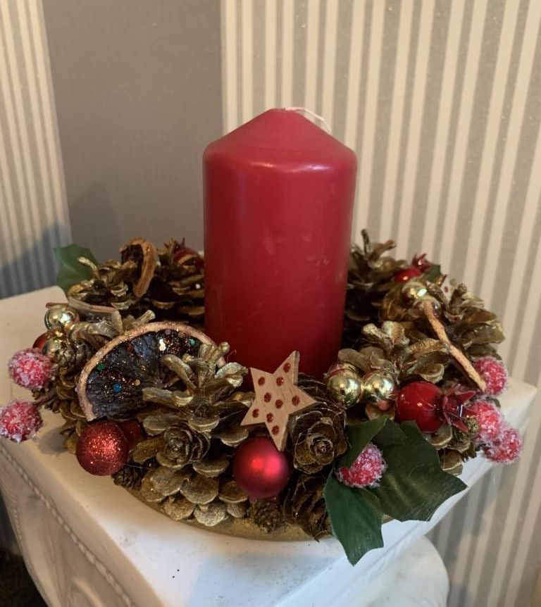 Jutta Bremekamps Weihnachtskranz mit haltbarer Dekoration wie Zimtsterne, Weihnachtskugeln, Tannenzapfen und goldener Kordel mit roter Kerze in der Mitte.