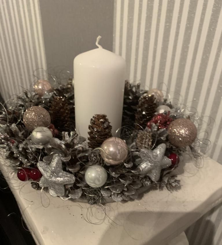 Weihnachtskranz aus haltbaren Material wie Weihnachtskugeln, Tannenzapfen und weißer Kerze in der Mitte
