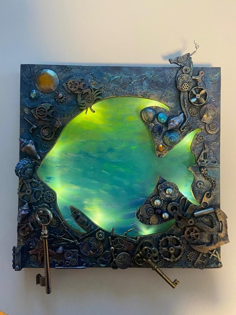 Elena Nizkovski betreibt ein ArtStudio. Steampunk ist ihre neue Passion. Der Fisch auf dem Bild ist in den Farben des Meeres gehalten, in dem die Sonne Spiegelungen erzeugt. Rundherum finden sich steampunktypische Embleme wie nautische Werkzeuge wie Steuerrad, Anker Sextant, Zirkel etc. ein.