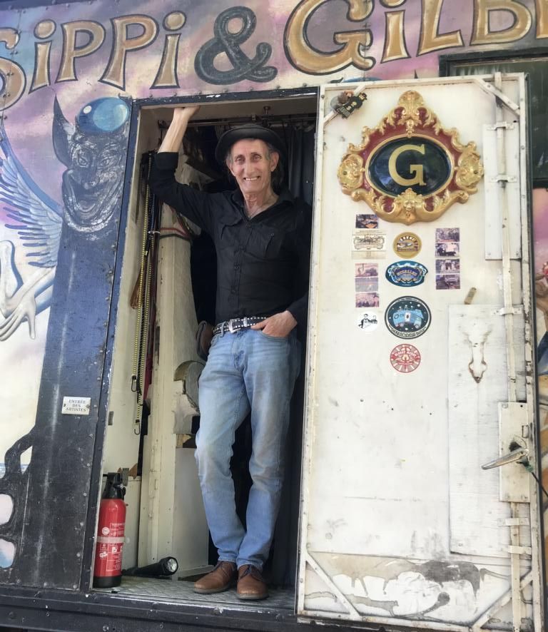 Gilbert, der Gaukler, steht in der Tür seines Camion. Es ist ein umgebauter Wagen, in dem er zu den Veranstaltungen reist, für die er gebucht ist. Darin ist alles enthalten, was er zum Leben und Arbeiten braucht.