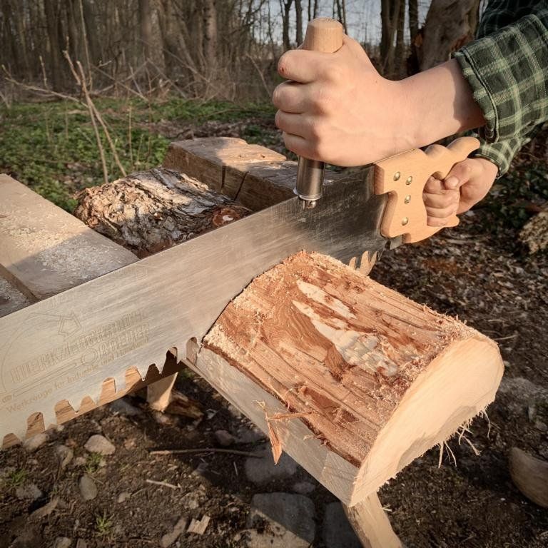 Ein Holzstück wird auf Länge zugeschnitten - alles ausschließlich mit Muskelkraft.