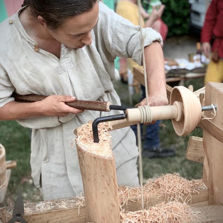Einer der Brüder bei der Arbeit an der Wippdrehbank. Eine Schüssel wird ausgehöhlt. Sie tragen dabei die traditionelle Kleidung.