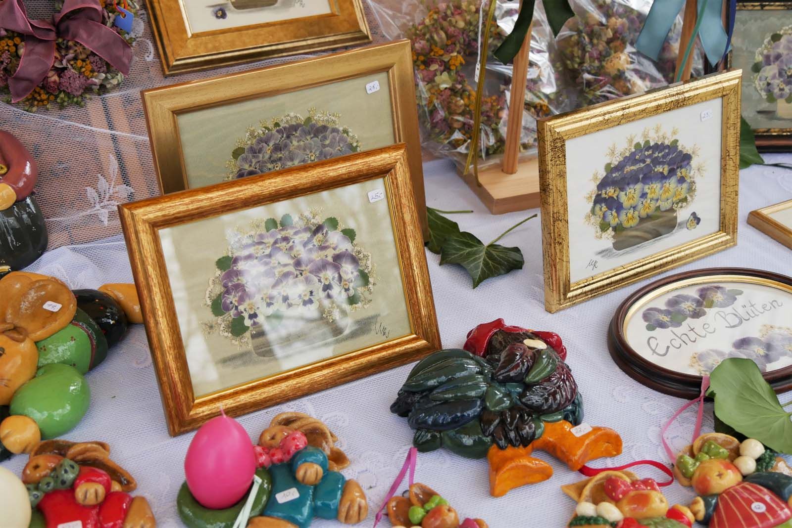 Im mühsamer Kleinarbeit gesammelte, gepresste Stiefmütterchen in Sträußen hinter Glas gebracht und gerahmt. Österliche Salzteigfiguren, bemalt und mit Lasur zum Glänzen gebracht sind sie eine bildhübsche Osterdekoration für jeden festlich gekleideten Tisch. Dies alles ist hübsch arrangiert beim kunsthandwerklichen Ostermarkt am Stand zu haben.