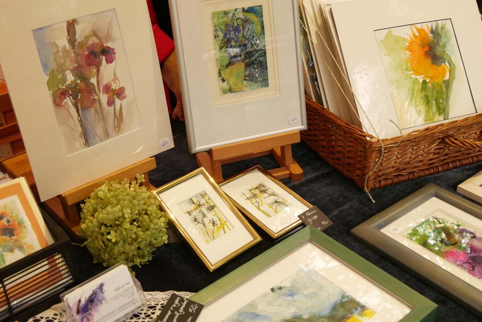 Kunststand mit Karten, Collagen und Aquarellen – liebevoll arrangiert mit Blumen und Staffeleien