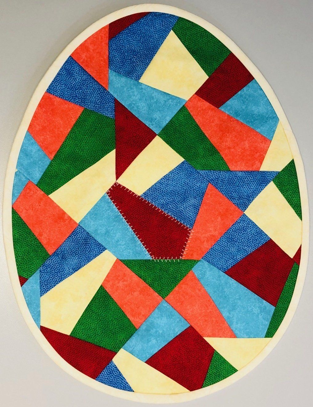 Karin Bolz eiförmige Patchworkdecke besteht aus vielen Teilstücken aus Stoff, die geometrischen Formen gehorchen.