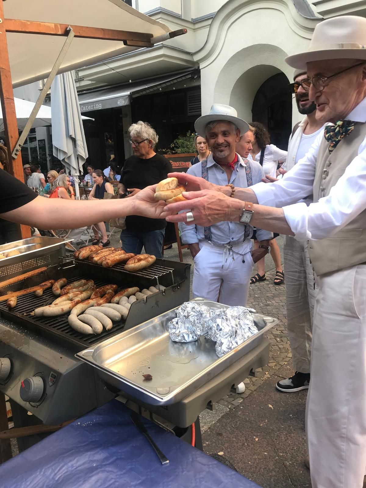 Günther Krabbenhöft lässt sich eine Original Thüringer Rostbratwurst am Stand von Bruderherz überreichen.