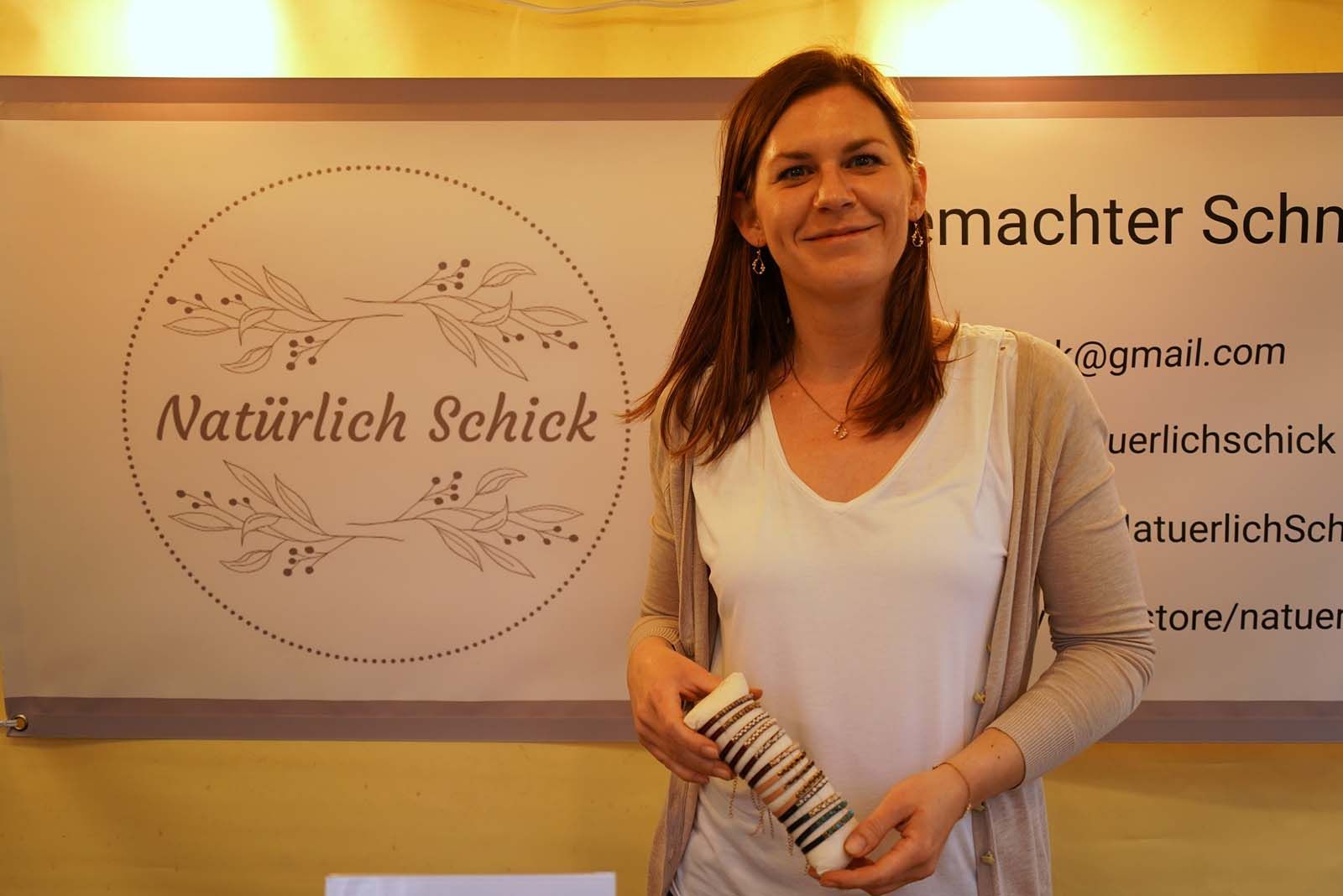 Marleen Mroseck von  Marleen Mroseck von Natürlich schick lächelt in die Kamera – in der Hand eine Stoffrolle mit Armbändern aus Edelsteinen, Perlen und Leder